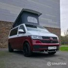 Volkswagen T6.1 short-wheelbase in Candy White and Fortana Red, fitted with a Spartan camper conversion, showing the clean interior layout, modular storage and signature slide-and-swivel bench.
