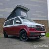 Volkswagen T6.1 short-wheelbase in Candy White and Fortana Red, fitted with a Spartan camper conversion, showing the clean interior layout, modular storage and signature slide-and-swivel bench.