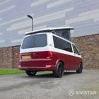 Volkswagen T6.1 short-wheelbase in Candy White and Fortana Red, fitted with a Spartan camper conversion, showing the clean interior layout, modular storage and signature slide-and-swivel bench.
