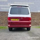 Volkswagen T6.1 short-wheelbase in Candy White and Fortana Red, fitted with a Spartan camper conversion, showing the clean interior layout, modular storage and signature slide-and-swivel bench.