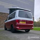 Volkswagen T6.1 short-wheelbase in Candy White and Fortana Red, fitted with a Spartan camper conversion, showing the clean interior layout, modular storage and signature slide-and-swivel bench.