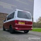 Volkswagen T6.1 short-wheelbase in Candy White and Fortana Red, fitted with a Spartan camper conversion, showing the clean interior layout, modular storage and signature slide-and-swivel bench.