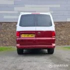 Volkswagen T6.1 short-wheelbase in Candy White and Fortana Red, fitted with a Spartan camper conversion, showing the clean interior layout, modular storage and signature slide-and-swivel bench.