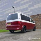 Volkswagen T6.1 short-wheelbase in Candy White and Fortana Red, fitted with a Spartan camper conversion, showing the clean interior layout, modular storage and signature slide-and-swivel bench.