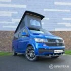 VW T6.1 Transporter in Ravenna Blue, fitted with a Spartan campervan conversion, parked outdoors. Clean lines, factory stance, and upgraded camper profile visible