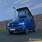 VW T6.1 Transporter in Ravenna Blue, fitted with a Spartan campervan conversion, parked outdoors. Clean lines, factory stance, and upgraded camper profile visible