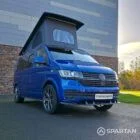 VW T6.1 Transporter in Ravenna Blue, fitted with a Spartan campervan conversion, parked outdoors. Clean lines, factory stance, and upgraded camper profile visible