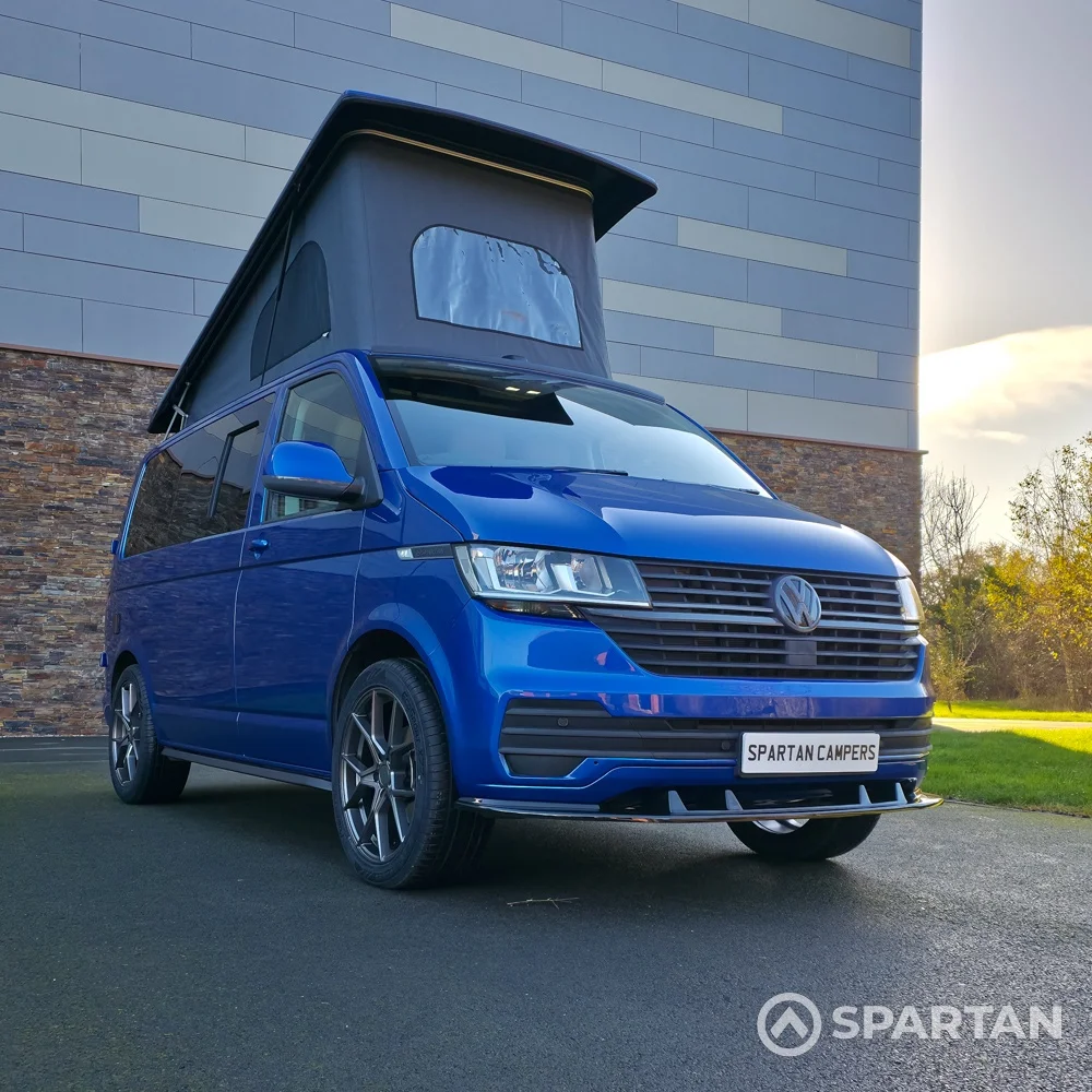 VW T6.1 Transporter in Ravenna Blue, fitted with a Spartan campervan conversion, parked outdoors. Clean lines, factory stance, and upgraded camper profile visible
