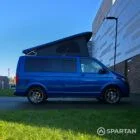 VW T6.1 Transporter in Ravenna Blue, fitted with a Spartan campervan conversion, parked outdoors. Clean lines, factory stance, and upgraded camper profile visible