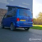 VW T6.1 Transporter in Ravenna Blue, fitted with a Spartan campervan conversion, parked outdoors. Clean lines, factory stance, and upgraded camper profile visible
