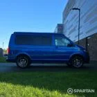 VW T6.1 Transporter in Ravenna Blue, fitted with a Spartan campervan conversion, parked outdoors. Clean lines, factory stance, and upgraded camper profile visible