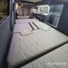 Interior of a Spartan Campers conversion with a Winter floor, indigo blue and taupe kitchen units, and dusk-grey upholstery, giving the space a calm, modern winter palette.