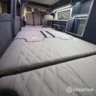 Interior of a Spartan Campers conversion with a Winter floor, indigo blue and taupe kitchen units, and dusk-grey upholstery, giving the space a calm, modern winter palette.