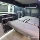 Interior of a Spartan Campers conversion with a Winter floor, indigo blue and taupe kitchen units, and dusk-grey upholstery, giving the space a calm, modern winter palette.