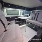 Interior of a Spartan Campers conversion with a Winter floor, indigo blue and taupe kitchen units, and dusk-grey upholstery, giving the space a calm, modern winter palette.