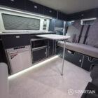 Interior of a Spartan Campers conversion with a Winter floor, indigo blue and taupe kitchen units, and dusk-grey upholstery, giving the space a calm, modern winter palette.