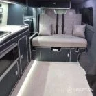 Interior of a Spartan Campers conversion with a Winter floor, indigo blue and taupe kitchen units, and dusk-grey upholstery, giving the space a calm, modern winter palette.