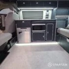 Interior of a Spartan Campers conversion with a Winter floor, indigo blue and taupe kitchen units, and dusk-grey upholstery, giving the space a calm, modern winter palette.