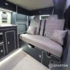 Interior of a Spartan Campers conversion with a Winter floor, indigo blue and taupe kitchen units, and dusk-grey upholstery, giving the space a calm, modern winter palette.
