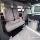 Interior of a Spartan Campers conversion with a Winter floor, indigo blue and taupe kitchen units, and dusk-grey upholstery, giving the space a calm, modern winter palette.