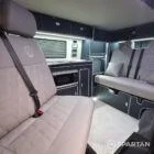 Interior of a Spartan Campers conversion with a Winter floor, indigo blue and taupe kitchen units, and dusk-grey upholstery, giving the space a calm, modern winter palette.