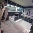 Interior of a Spartan Campers conversion with a Winter floor, indigo blue and taupe kitchen units, and dusk-grey upholstery, giving the space a calm, modern winter palette.