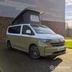VW Transporter T7 campervan with full Spartan Campers conversion in white and military green, drivers front quarter with the poptop roof up