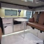VW T7 Transporter with Spartan campervan conversion living space showcasing the kitchen appliances and seating configuration with the dining table out