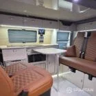 VW T7 Transporter with Spartan campervan conversion living space showcasing the kitchen appliances and seating configuration with the rock and roll bed up and front bench seat facing the rear