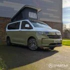 VW Transporter T7 campervan with full Spartan Campers conversion in white and military green, drivers front quarter with the poptop roof up