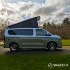 VW Transporter T7 campervan with full Spartan Campers conversion in white and military green, drivers side with the poptop roof up