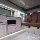 VW T7 Transporter with Spartan campervan conversion interior with winter flooring, latte and amber oak kitchen and fudge upholstery. Kitchen with fridge freezer, microwave, fabworks r&r bed and savvy van digital display