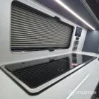 VW T7 Transporter with Spartan campervan conversion. Interior view with blizzard flooring, storm cloud and light grey kitchen showcasing the sink and twin gas burner with the lid down