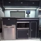 VW T7 Transporter with Spartan campervan conversion. Interior view with blizzard flooring, storm cloud and light grey kitchen and dust grey upholstery. showcasing the microwave and fridge freezer