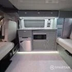 Spartan campers VW campervan with winter flooring, Italian Reed Green and Latte kitchen with Cookie upholstery. Fitted with a microwave, fridge/freezer, sink, wireless fast charger, rock and roll bed, and swivel and slide passenger bench seat