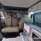 VW T6.1 interior of a Spartan campervan conversion, fitted with altro flooring, ivory and indigo blue kitchen and taupe upholstery. Featuring a microwave, fridge/ freezer, wireless fast charger, sink, double gas burner and central control panels
