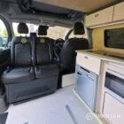 VW T7 Short wheelbase Spartan campervan interior with a passenger bench seat and mobiframe bed on rails. Winter flooring, latte and winchester oak kitchen