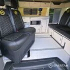 VW T7 Short wheelbase Spartan campervan interior with a passenger bench seat and mobiframe bed on rails. Winter flooring, latte and winchester oak kitchen