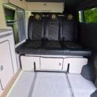 VW T7 Short wheelbase Spartan campervan interior with a passenger bench seat and mobiframe bed on rails. Winter flooring, latte and winchester oak kitchen