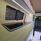 VW T7 Short wheelbase Spartan campervan interior with a passenger bench seat and mobiframe bed on rails. Winter flooring, latte and winchester oak kitchen