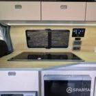 VW T7 Short wheelbase Spartan campervan interior with a passenger bench seat and mobiframe bed on rails. Winter flooring, latte and winchester oak kitchen