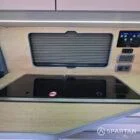 VW T7 Short wheelbase Spartan campervan interior with a passenger bench seat and mobiframe bed on rails. Winter flooring, latte and winchester oak kitchen