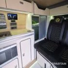 VW T7 Short wheelbase Spartan campervan interior with a passenger bench seat and mobiframe bed on rails. Winter flooring, latte and winchester oak kitchen