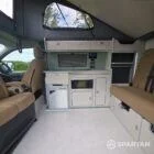 SWB VW T7 with Spartan Campers conversion, interior with winter flooring, latte and Italian reed green kitchen, liquor upholstery. Including a microwave, fridge/ freezer, rock and roll bed, double gas burner and sink
