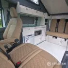SWB VW T7 with Spartan Campers conversion, interior with winter flooring, latte and Italian reed green kitchen, liquor upholstery. Including a microwave, fridge/ freezer, rock and roll bed, double gas burner and sink