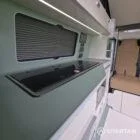 SWB VW T7 with Spartan Campers conversion, interior with winter flooring, latte and Italian reed green kitchen, liquor upholstery. Including a microwave, fridge/ freezer, rock and roll bed, double gas burner and sink