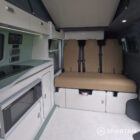 SWB VW T7 with Spartan Campers conversion, interior with winter flooring, latte and Italian reed green kitchen, liquor upholstery. Including a microwave, fridge/ freezer, rock and roll bed, double gas burner and sink