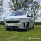 VW T7 in Meadow Green, front passengers quarter, pop top down