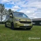 VW T7 SWB Spartan Campers campervan in warm metallic green, drivers front quarter with pop top roof down