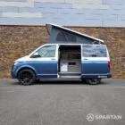 Passenger side profile with the elevating roof raised, highlighting the full camper conversion.